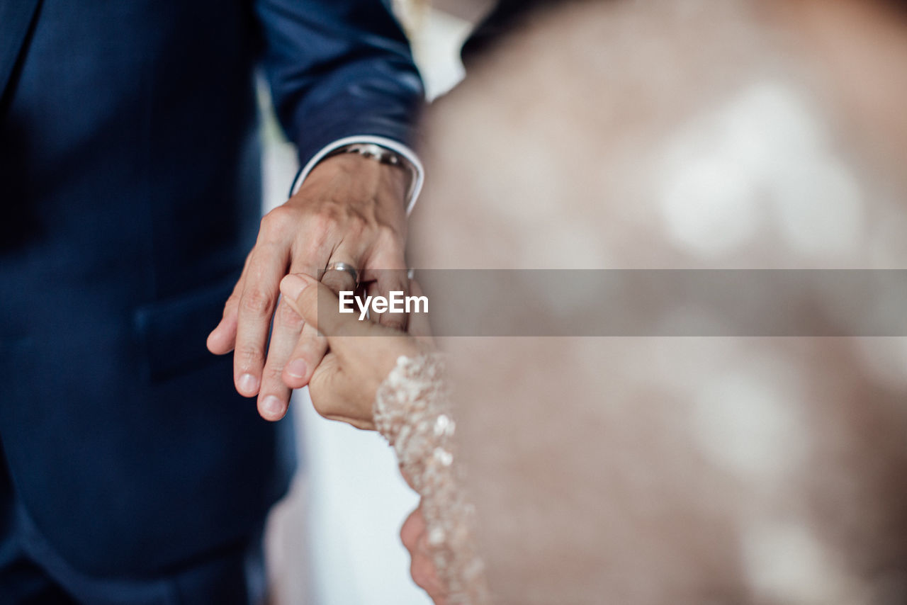 Midsection of couple holding hands in wedding ceremony