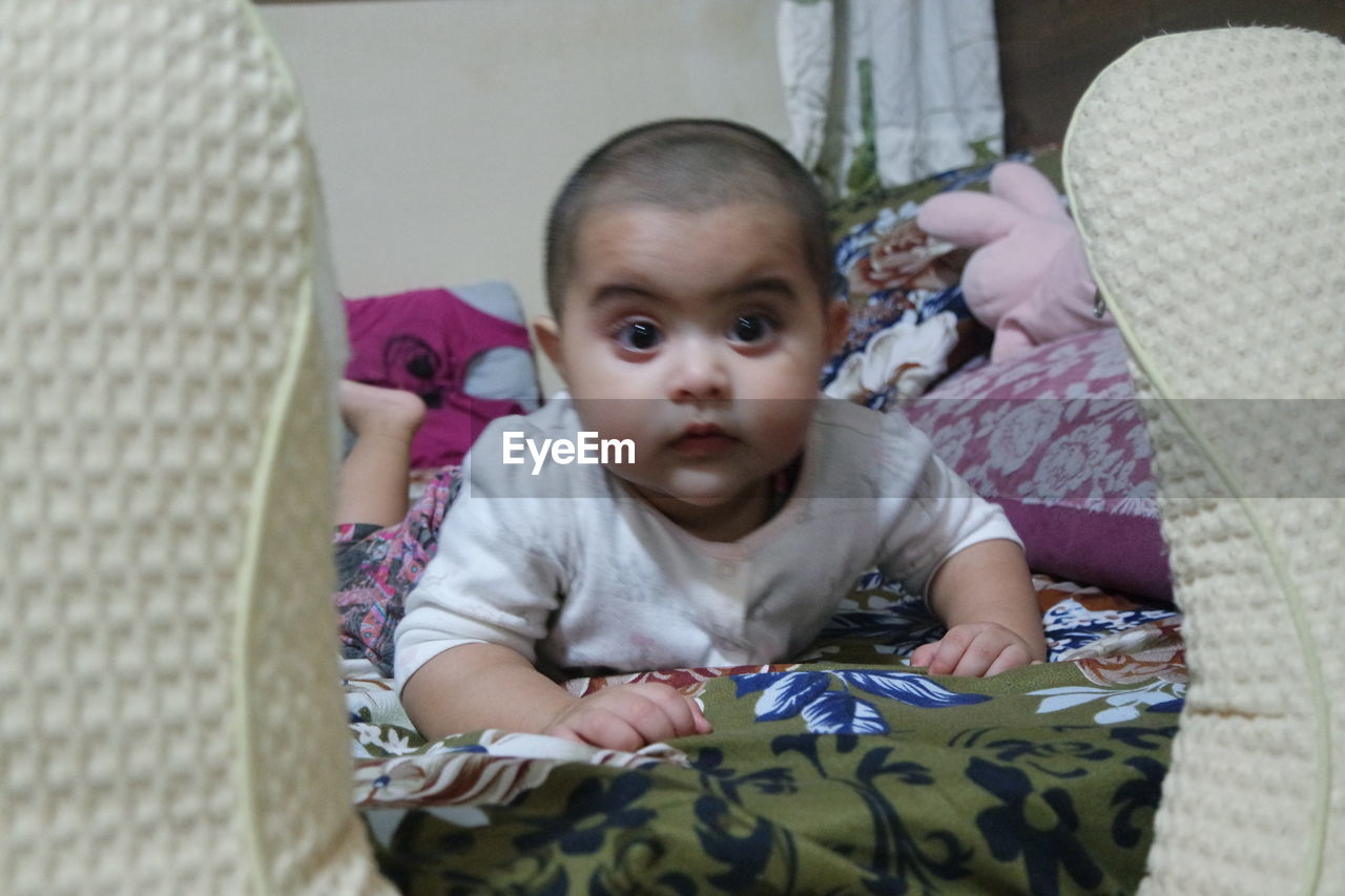 PORTRAIT OF CUTE BABY BOY LYING ON BED AT HOME