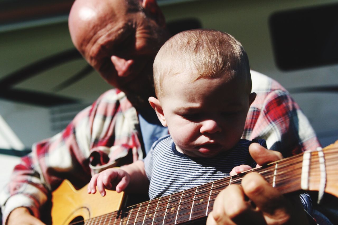 Midsection of man playing guitar with child