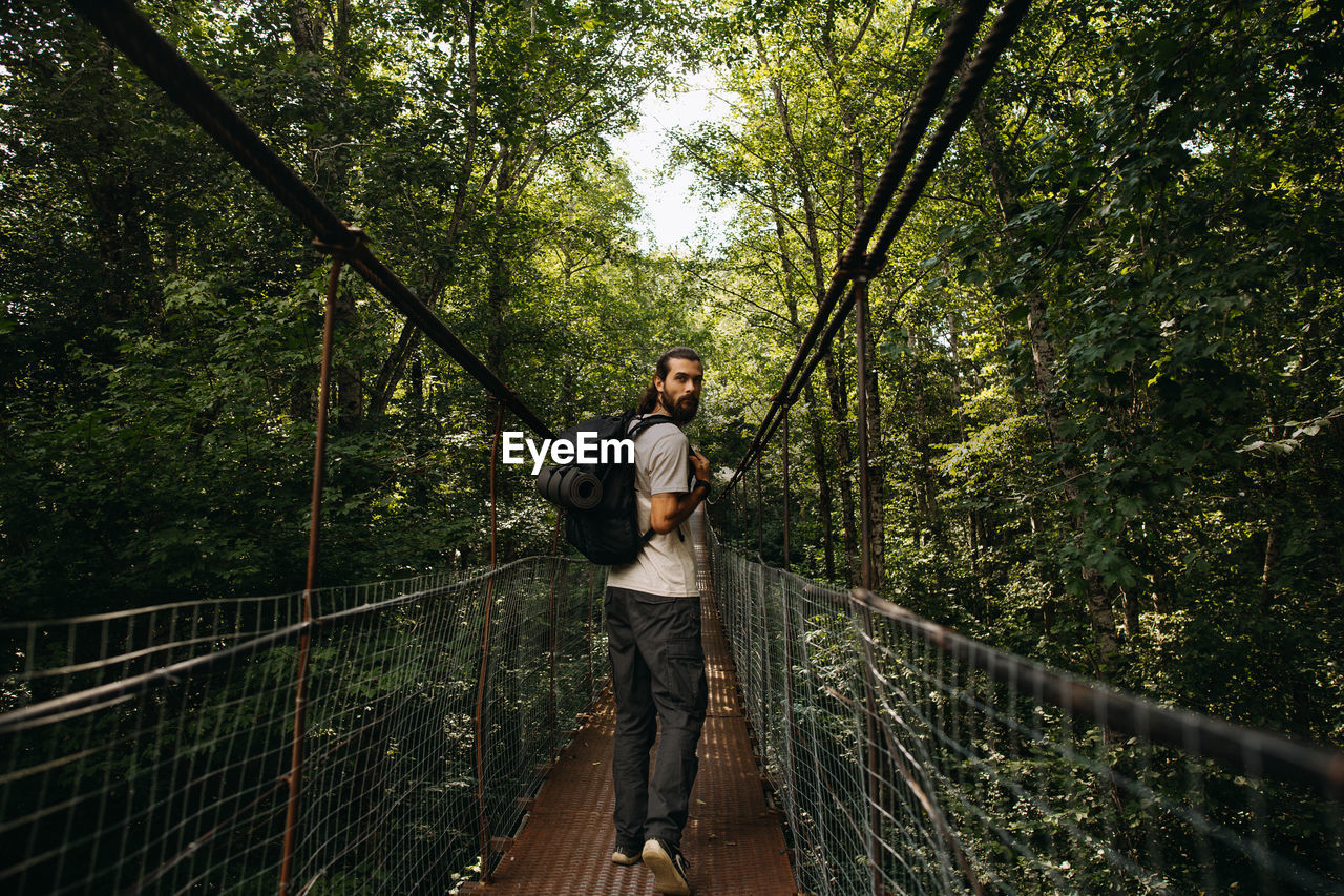 Man standing on footbridge in forest