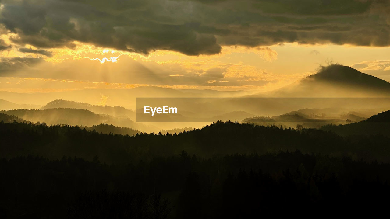 SCENIC VIEW OF SILHOUETTE MOUNTAINS AGAINST ORANGE SKY