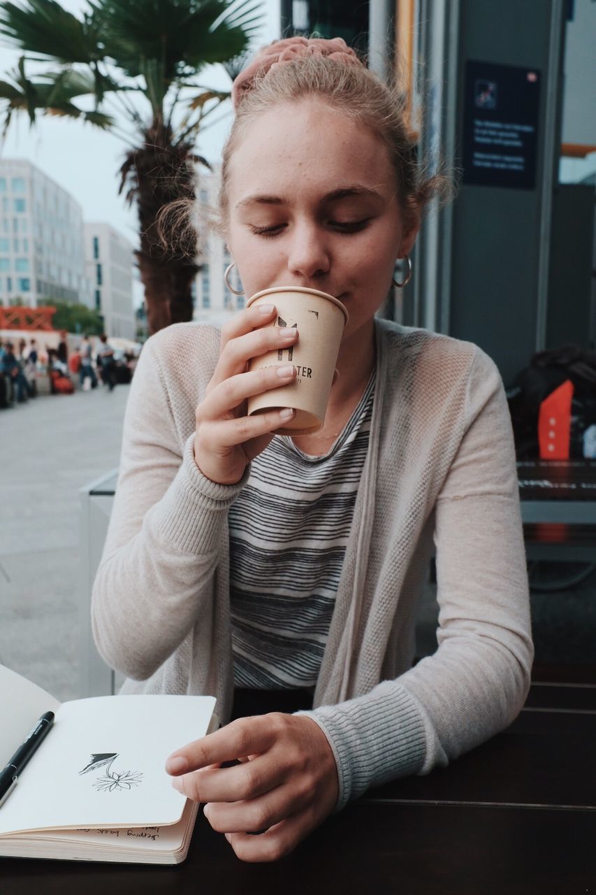 CLOSE-UP OF A YOUNG WOMAN SITTING AT TABLE