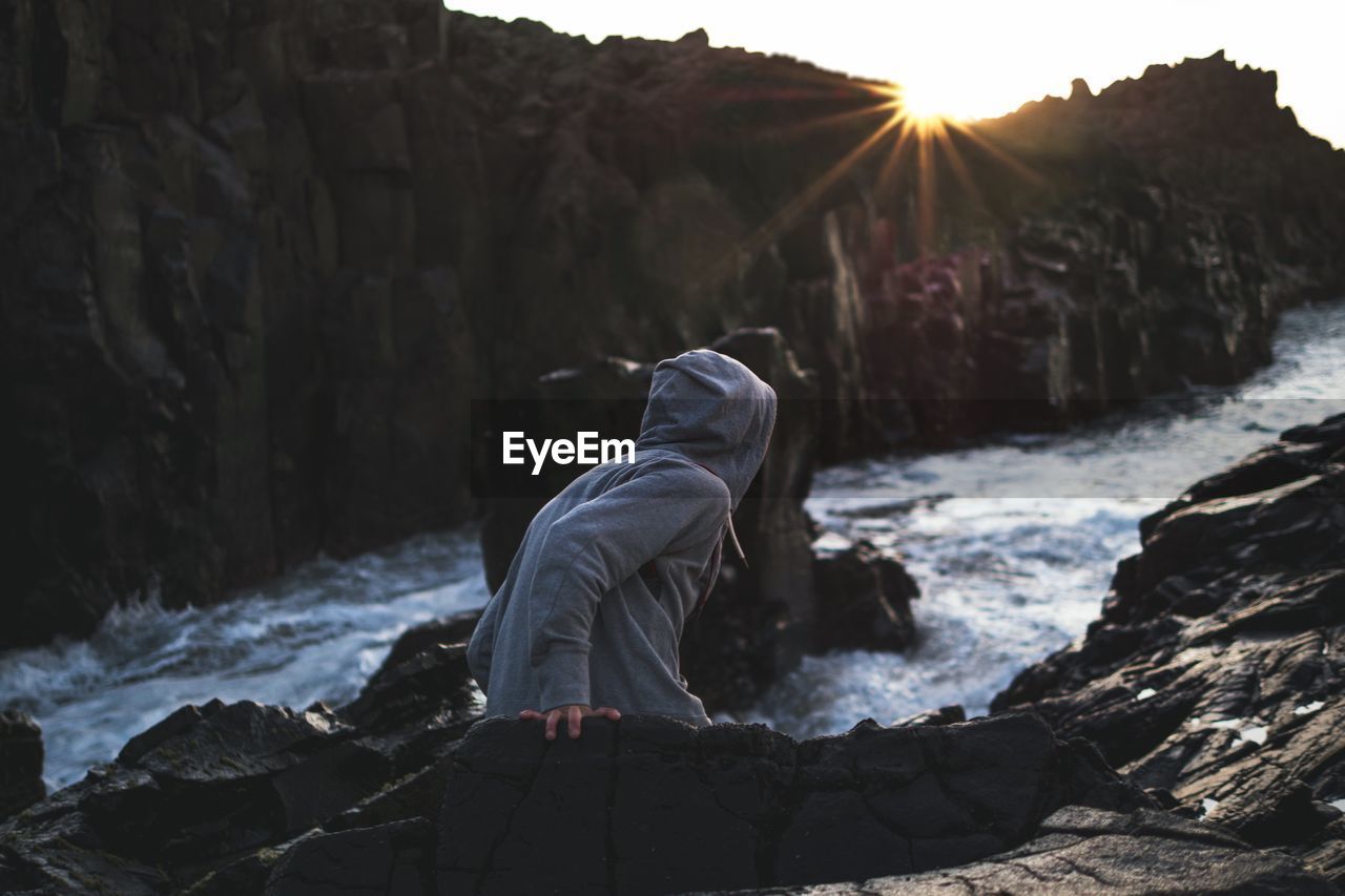 Rear view of person standing on rocks against river