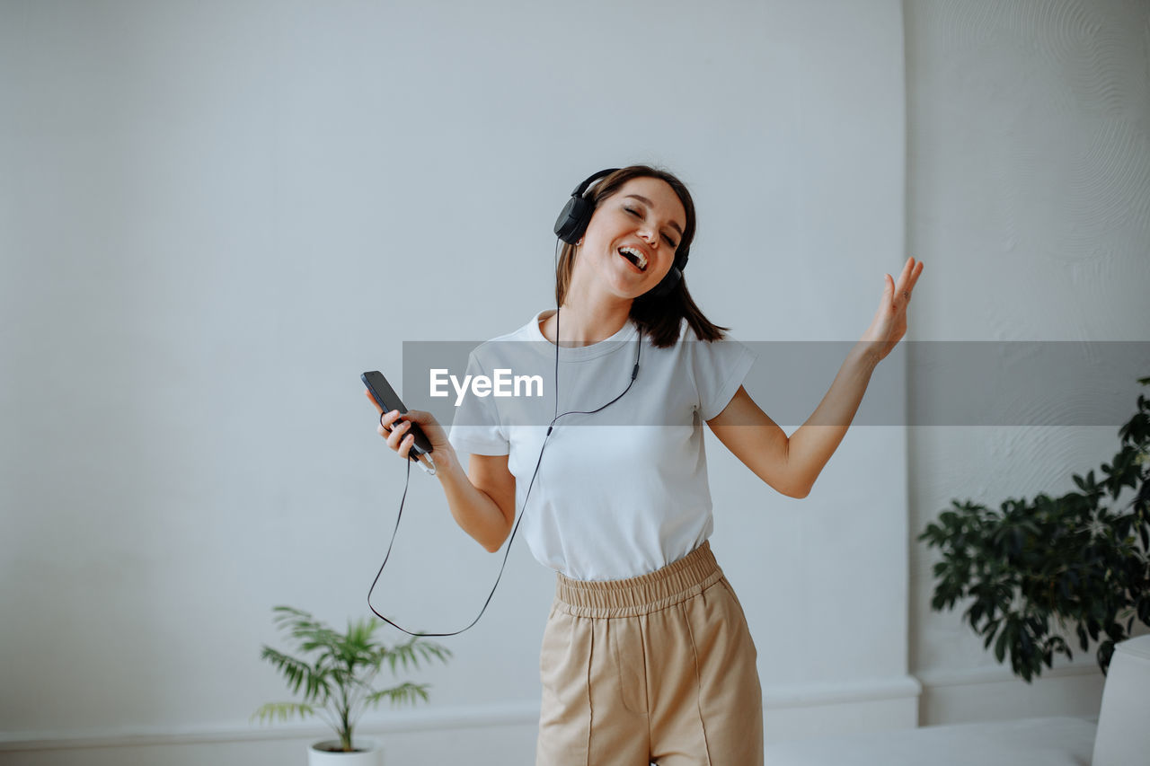 Young girl at home listening to music with headphones and dancing