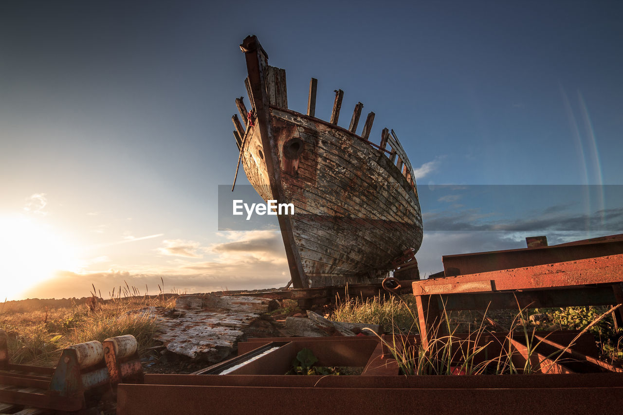 Abandoned boat against sky during sunset