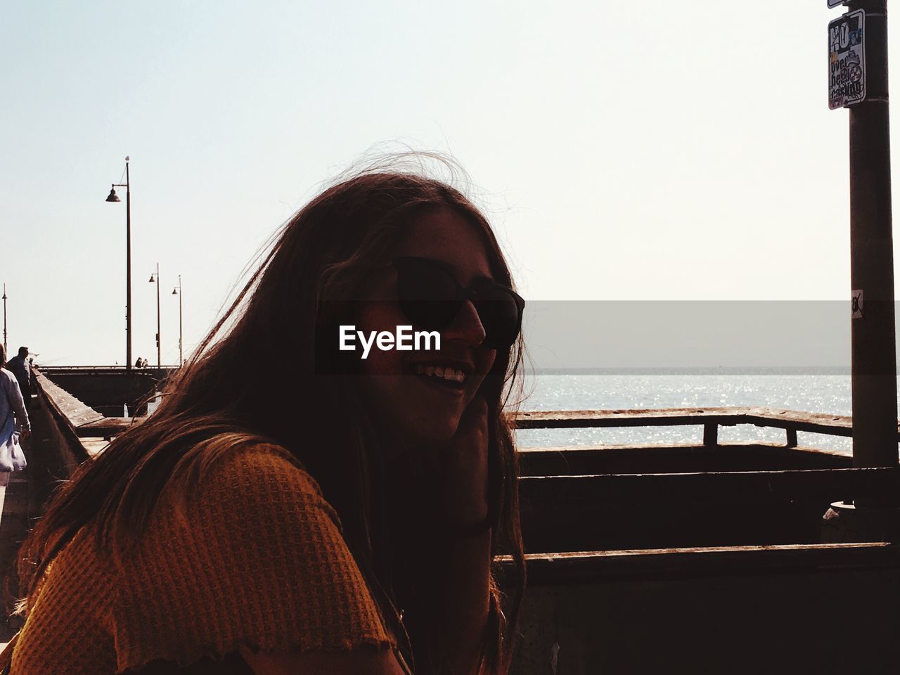 Portrait of smiling woman in sunglasses at sea against clear sky