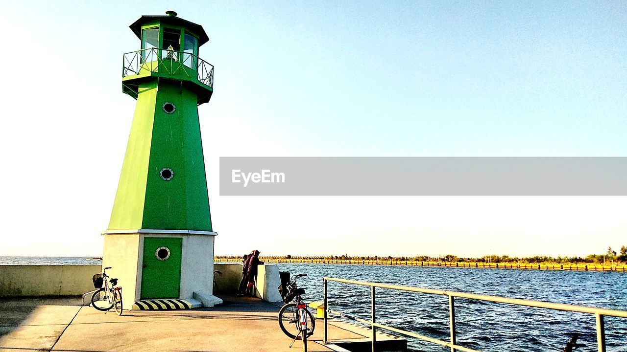 BICYCLE BY LIGHTHOUSE AGAINST SEA