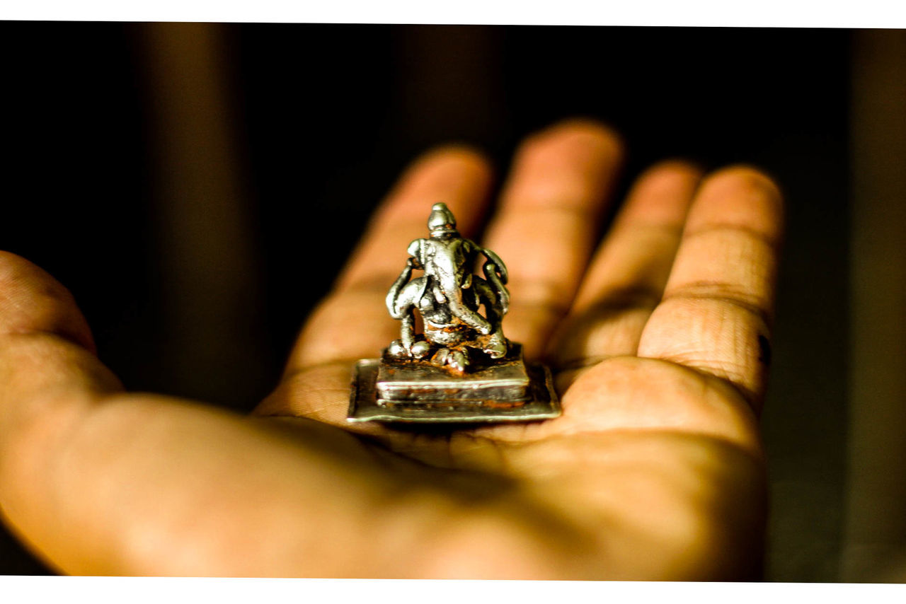 Close-up of hand holding ganesha figurine at home