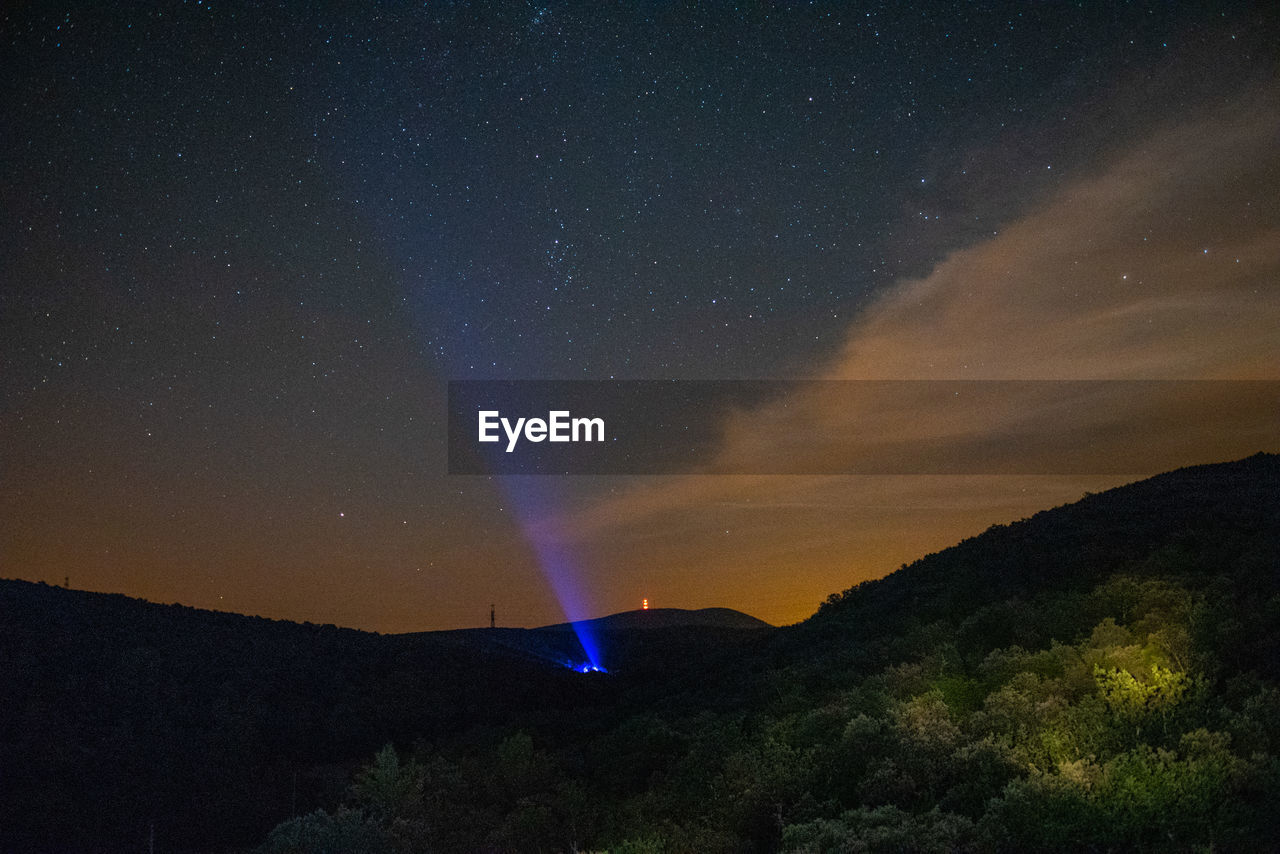 SCENIC VIEW OF ILLUMINATED MOUNTAIN AGAINST SKY AT NIGHT