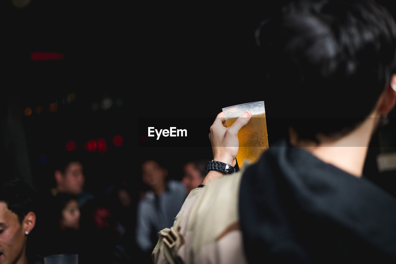 Rear view of man holding beer at nightclub