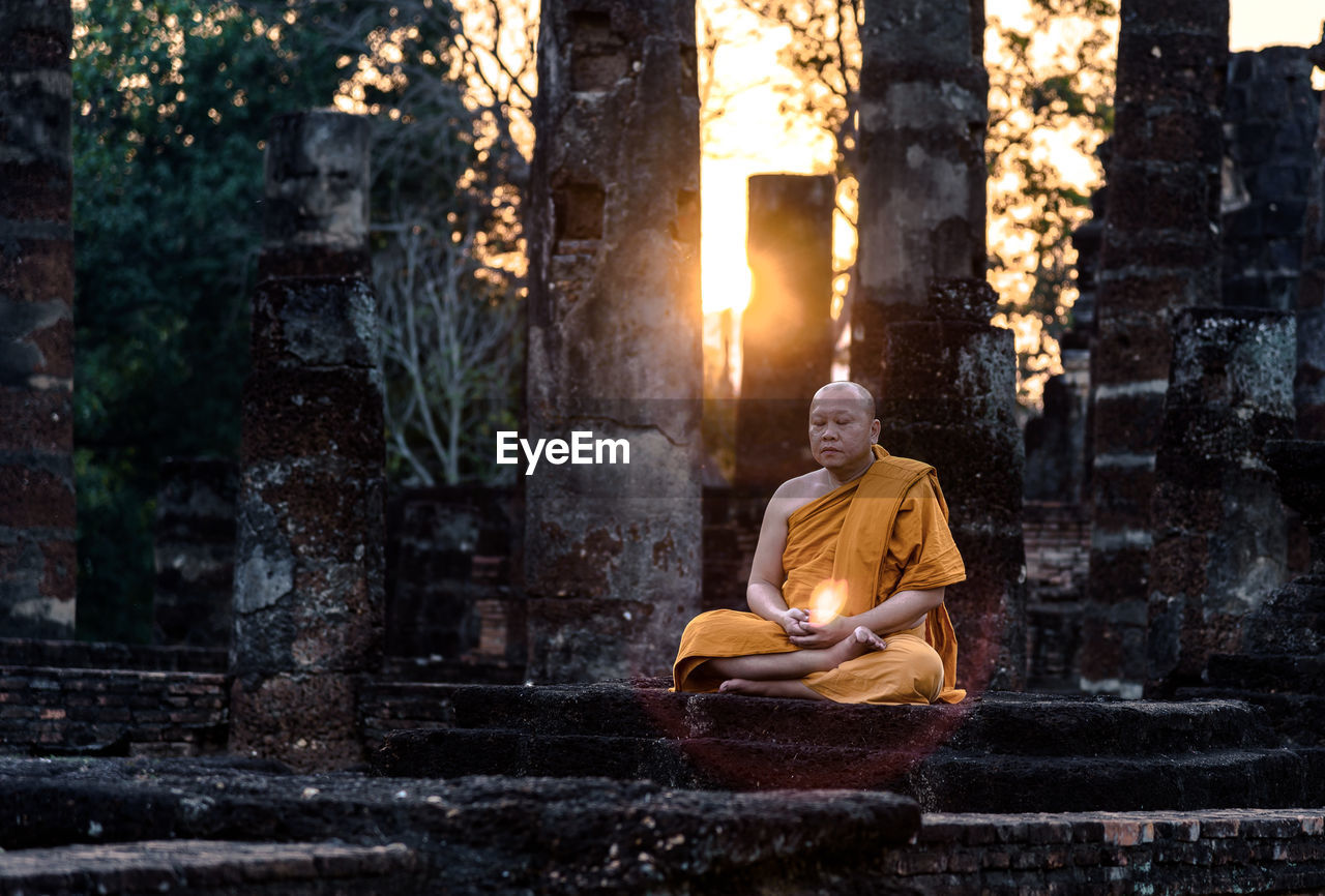 Monk meditating at old ruin temple