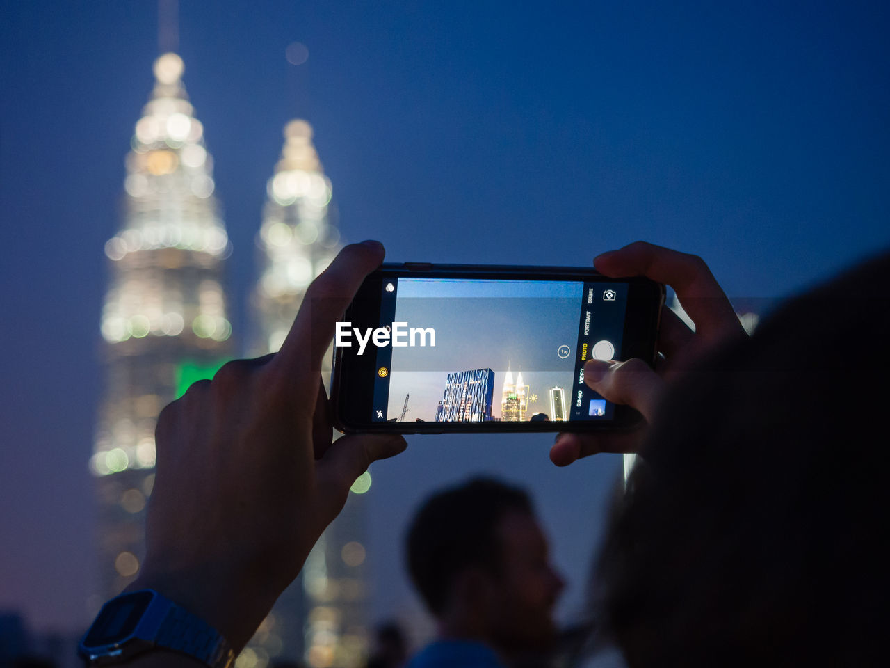 Low section of man photographing using smart phone against sky