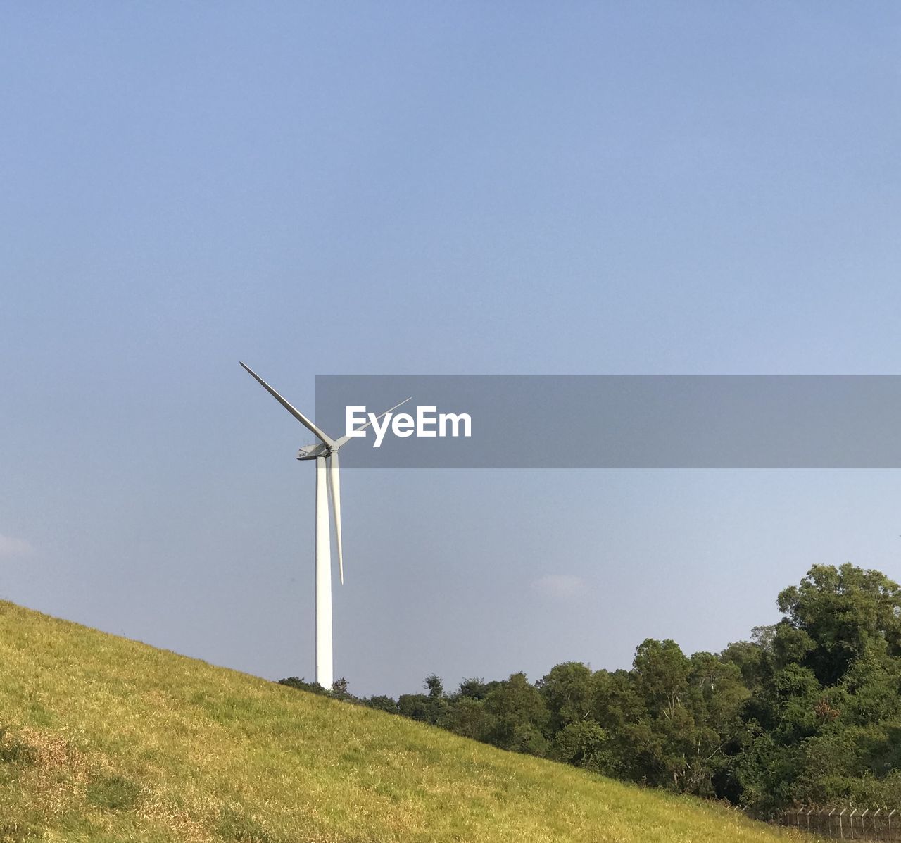 WINDMILLS ON FIELD AGAINST SKY