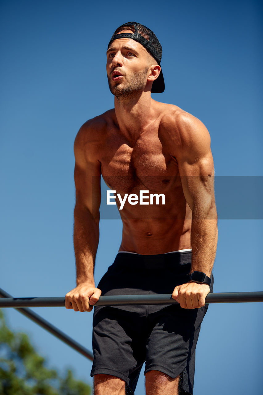 low angle view of shirtless man exercising against sky