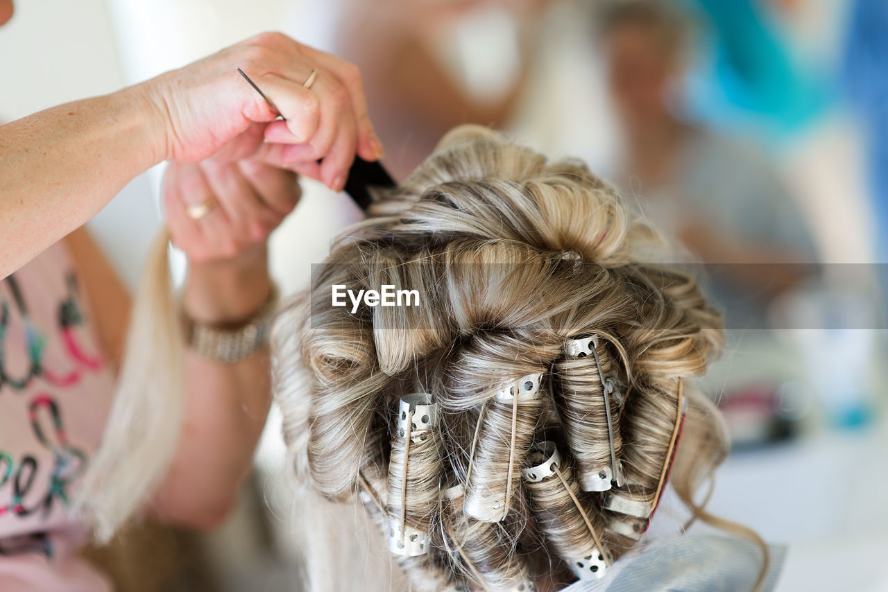 Cropped image of hairdresser styling customer hair in salon