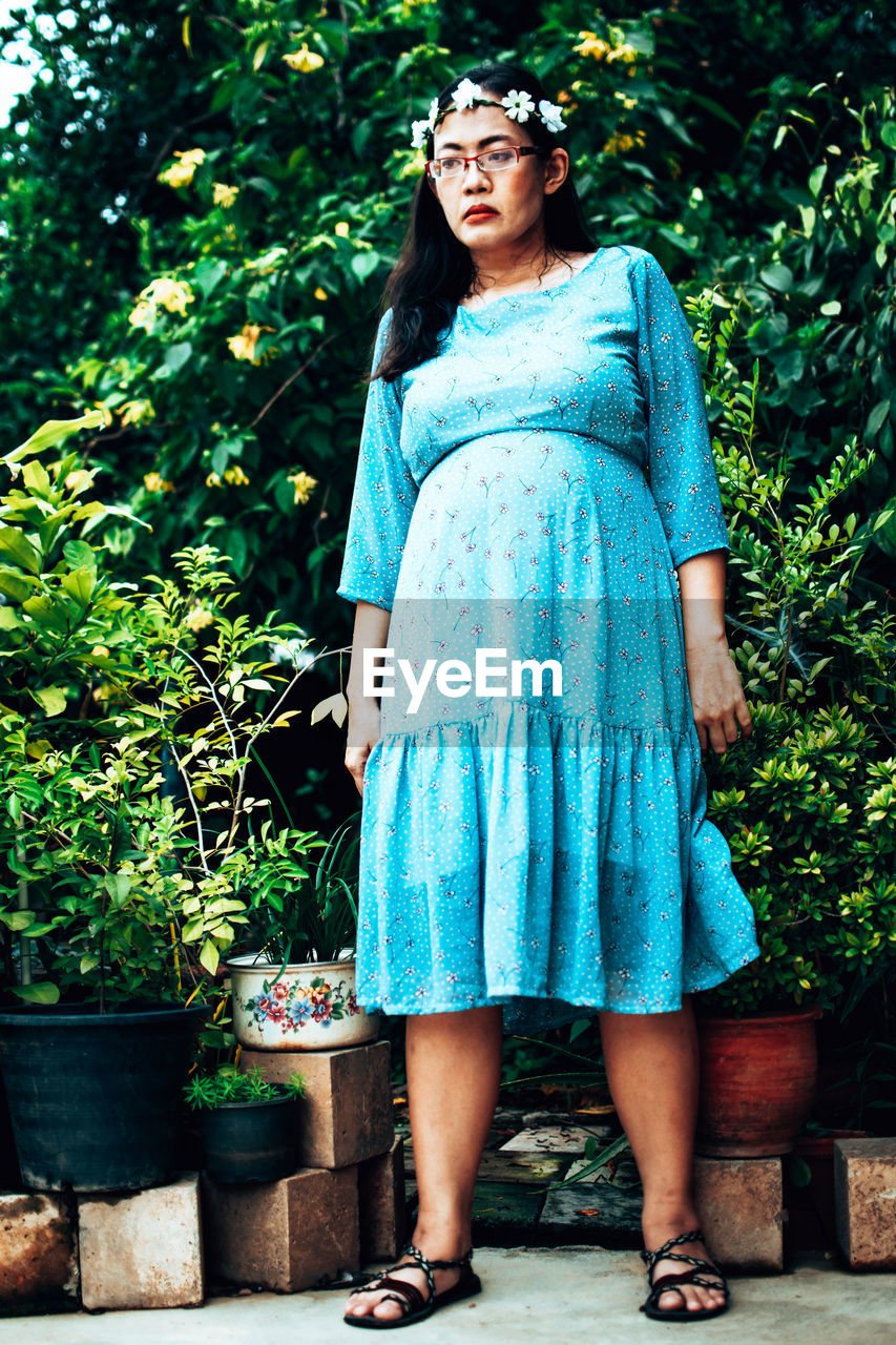 Portrait of a beautiful young woman standing in flower pot