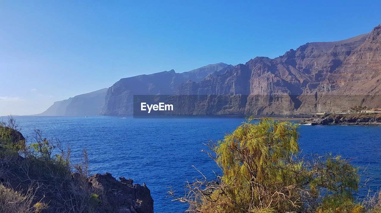 Scenic view of rocky cliffs against clear blue sky