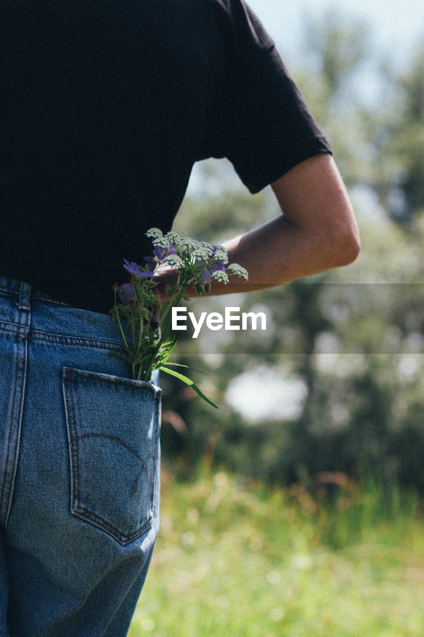 Midsection of woman with flowers in pocket