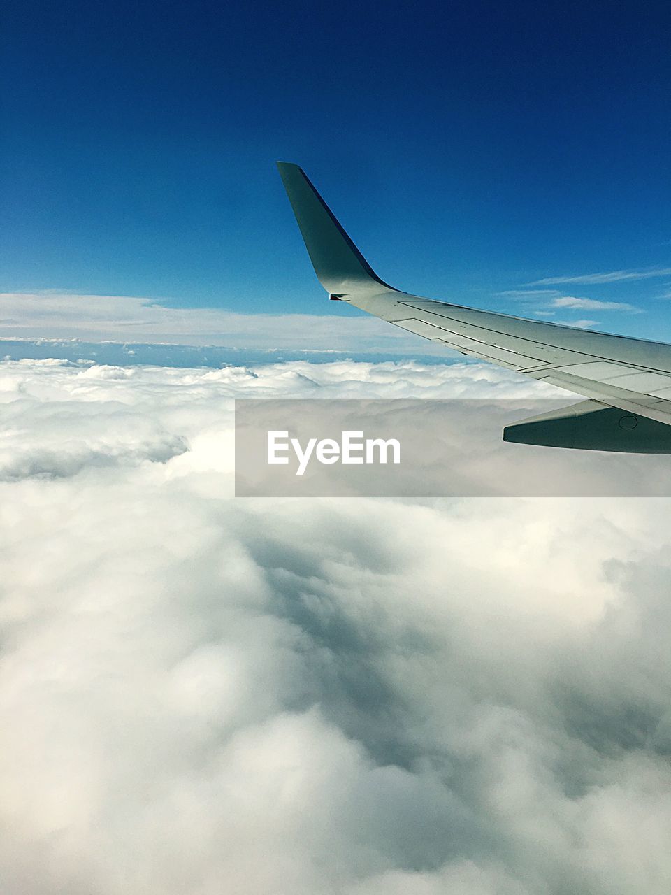 CROPPED IMAGE OF AIRPLANE WING OVER CLOUDS