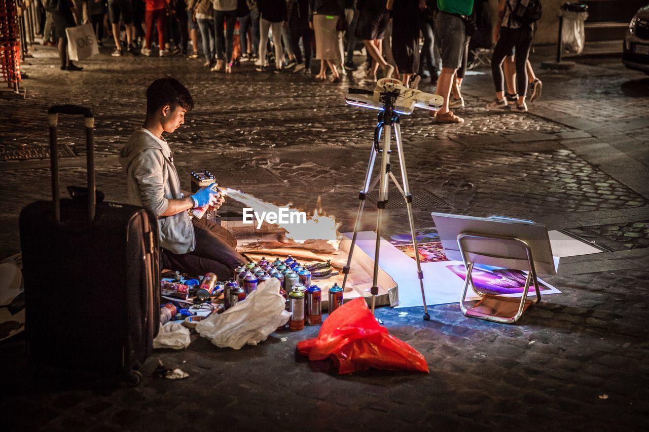 REAR VIEW OF WOMAN SITTING ON FLOOR AT MARKET