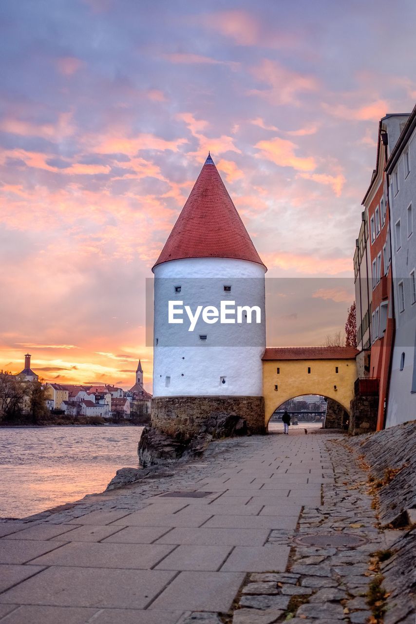 Building by sea against sky during sunset