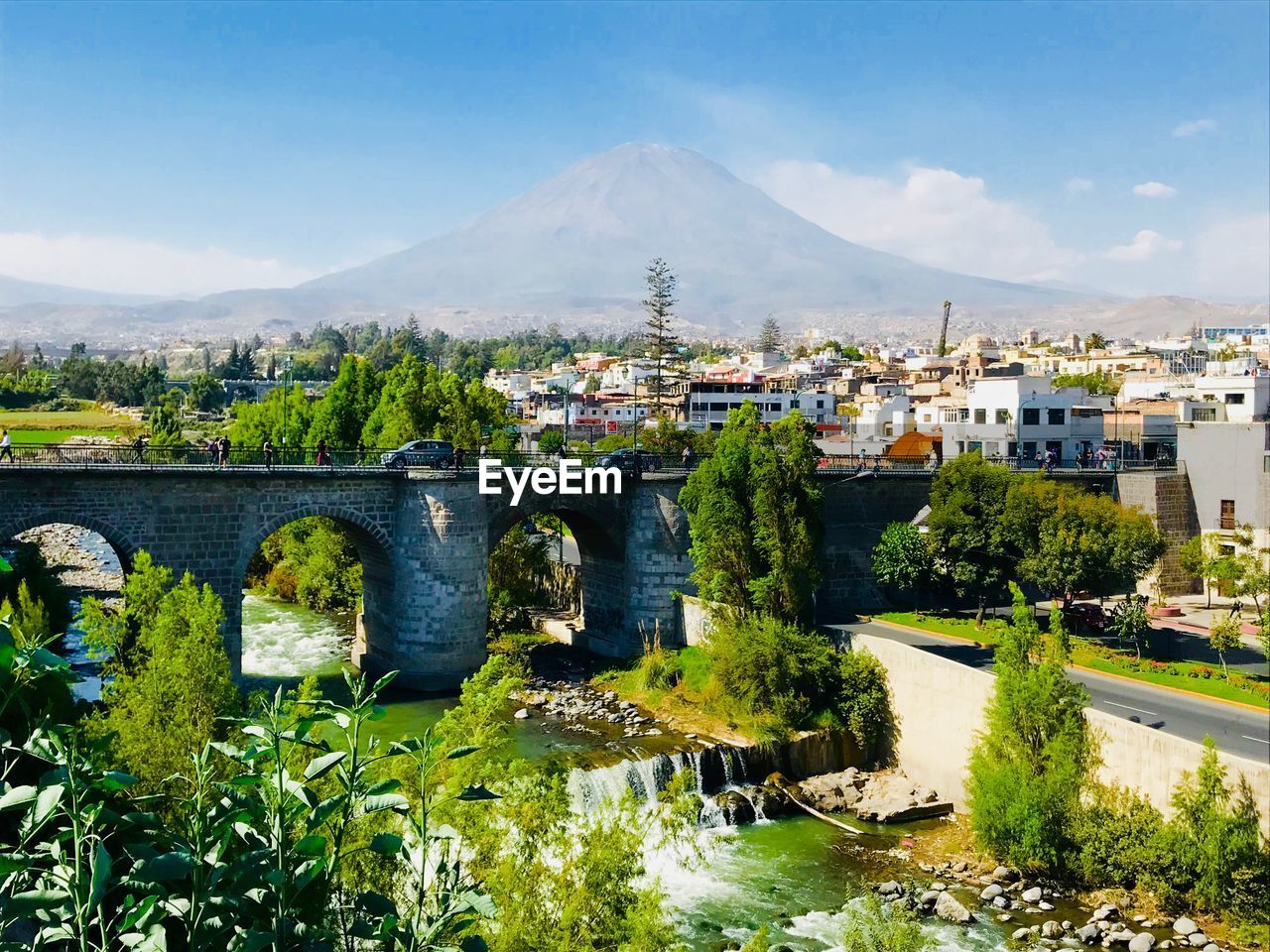 Bridge over river by buildings in city against sky