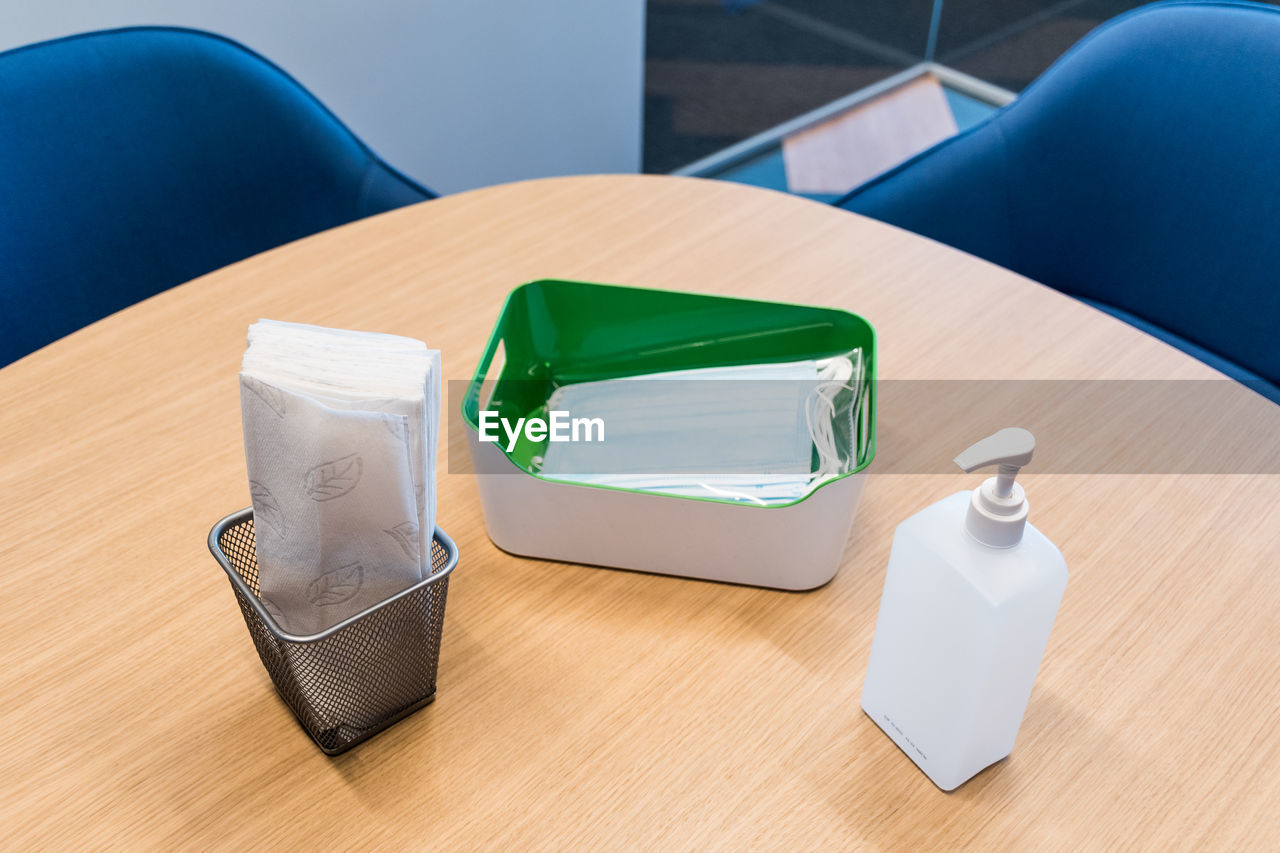 High angle view of hand sanitizer and surgical mask on table