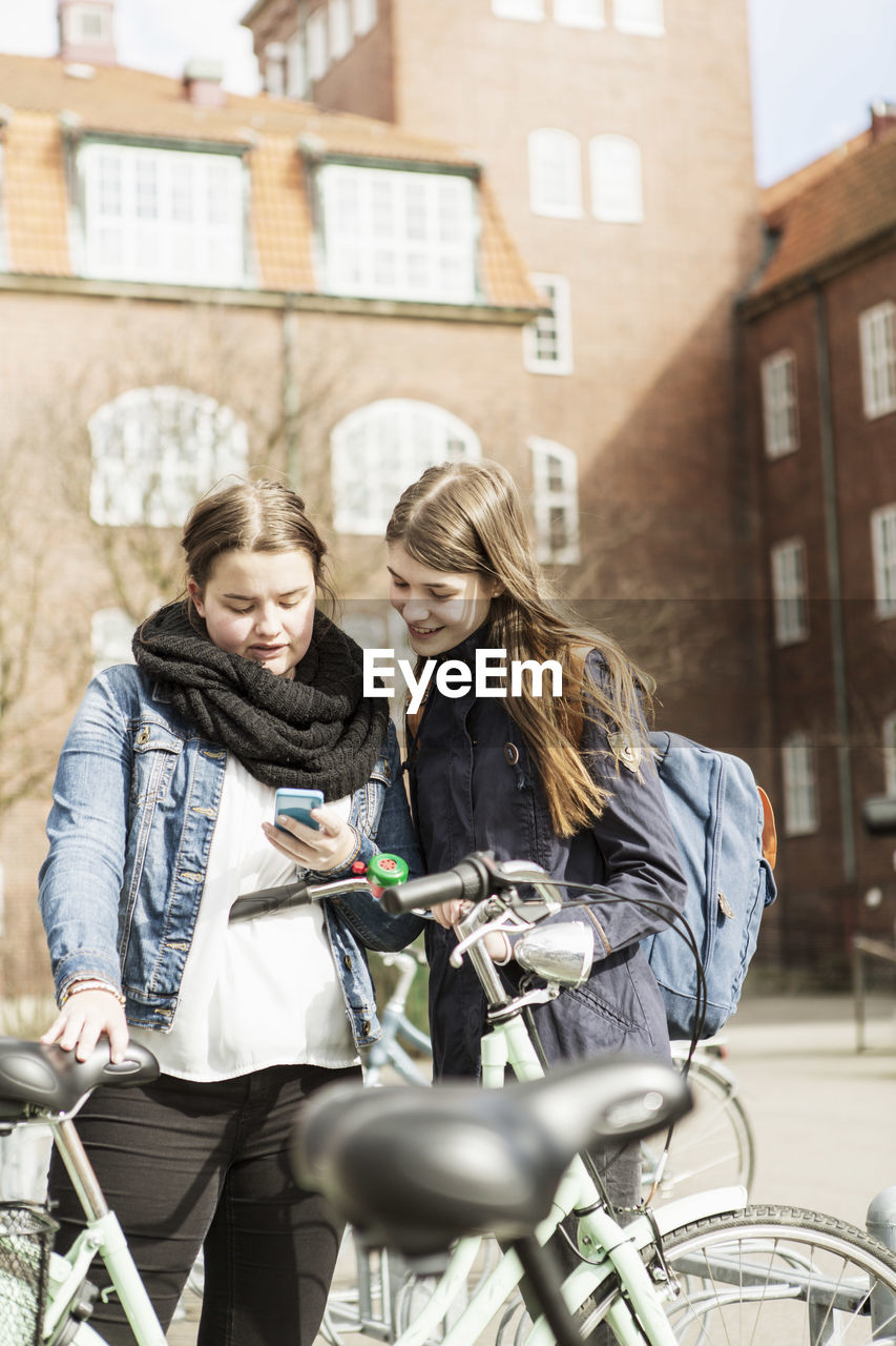 Young schoolgirls using mobile phone outside school building