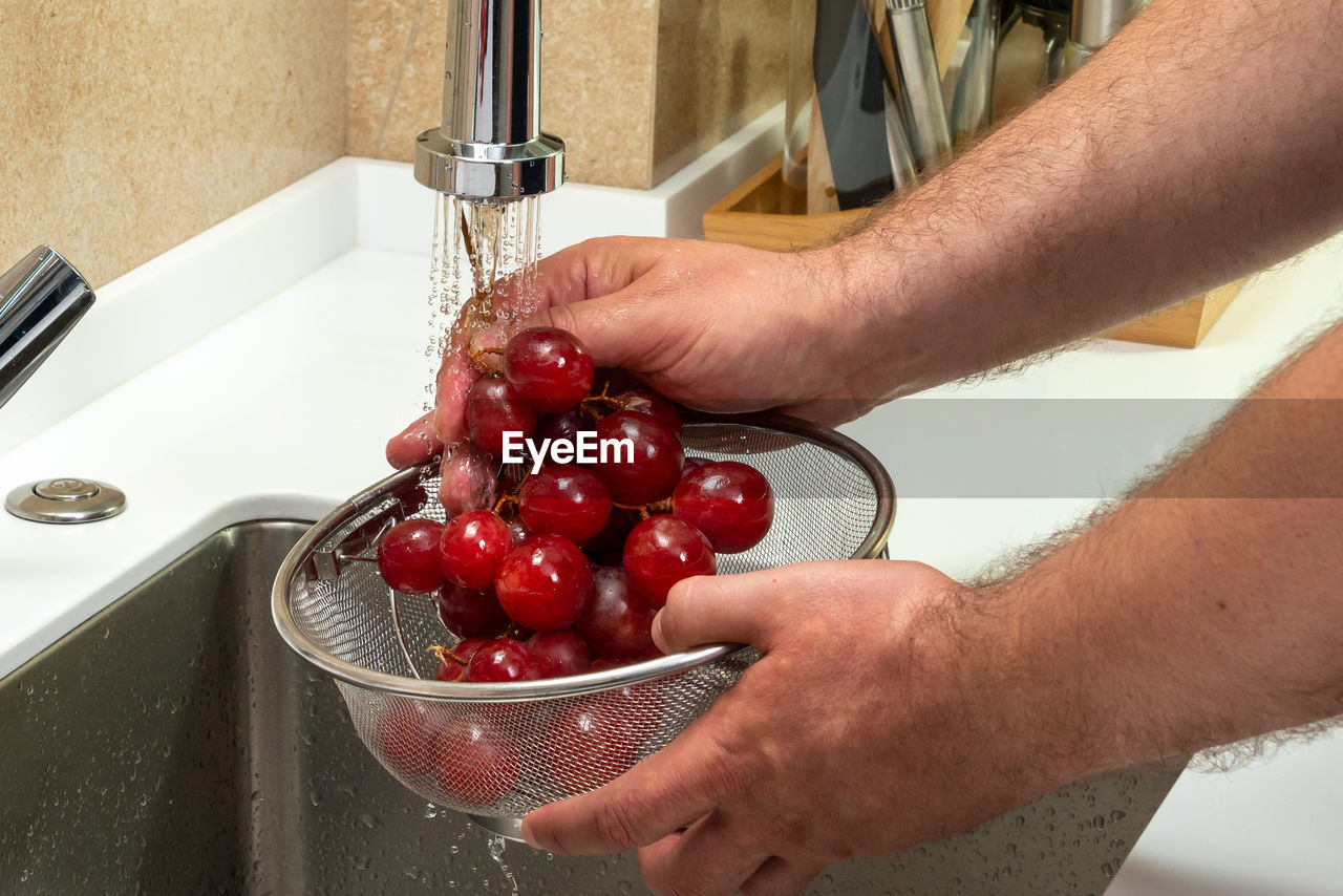 midsection of man washing hands in sink