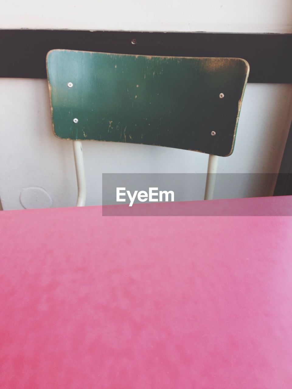 Close up image of a chair and pink table surface