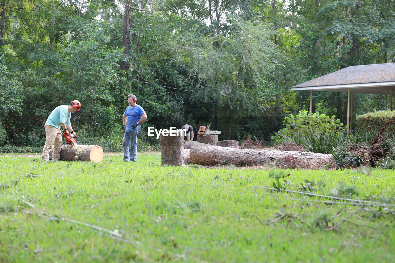 MEN STANDING ON FIELD AGAINST TREES