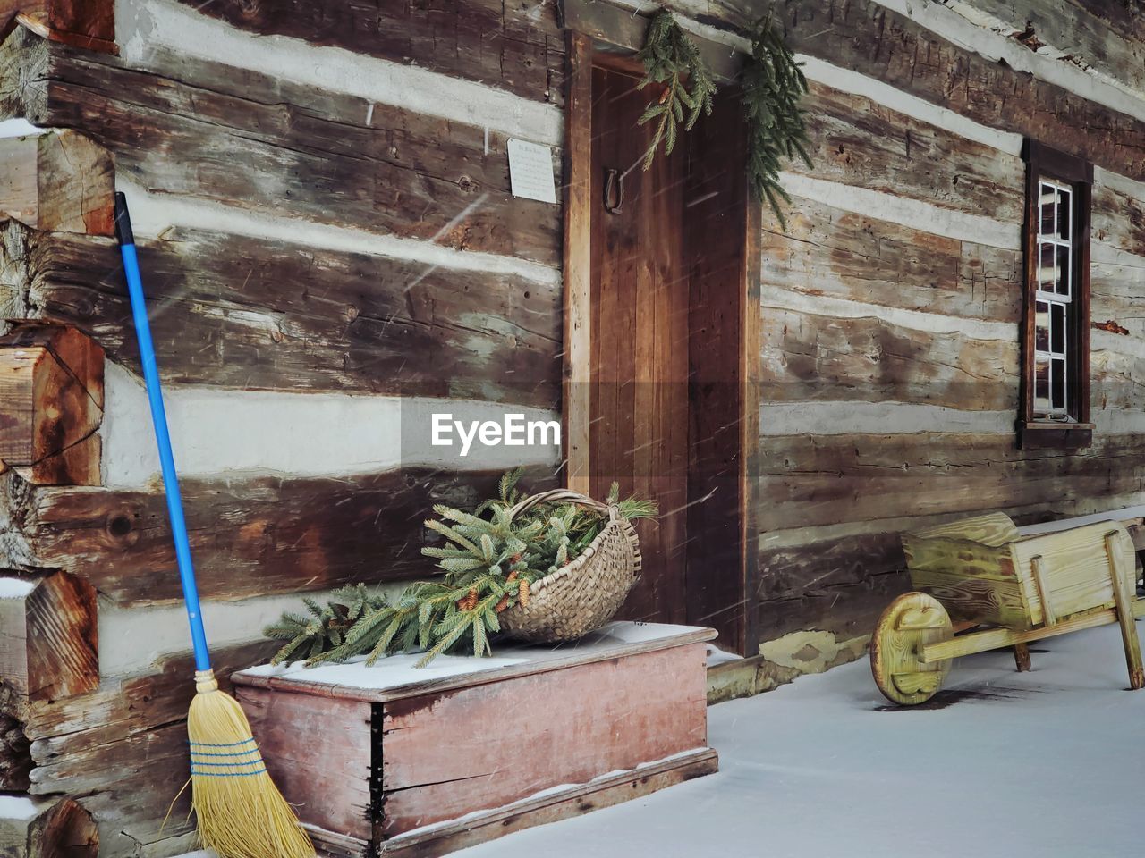 Front porch of a log cabin in winter with pine boughs and hand made wooden carr