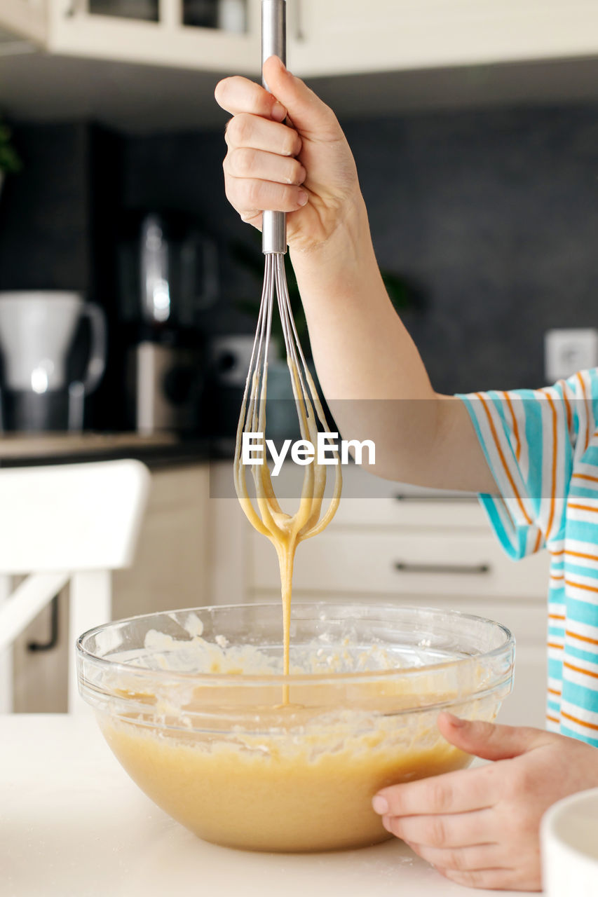 Close-up of a whisk with dough. the boy is kneading the dough for a pie or a cookie. the dough