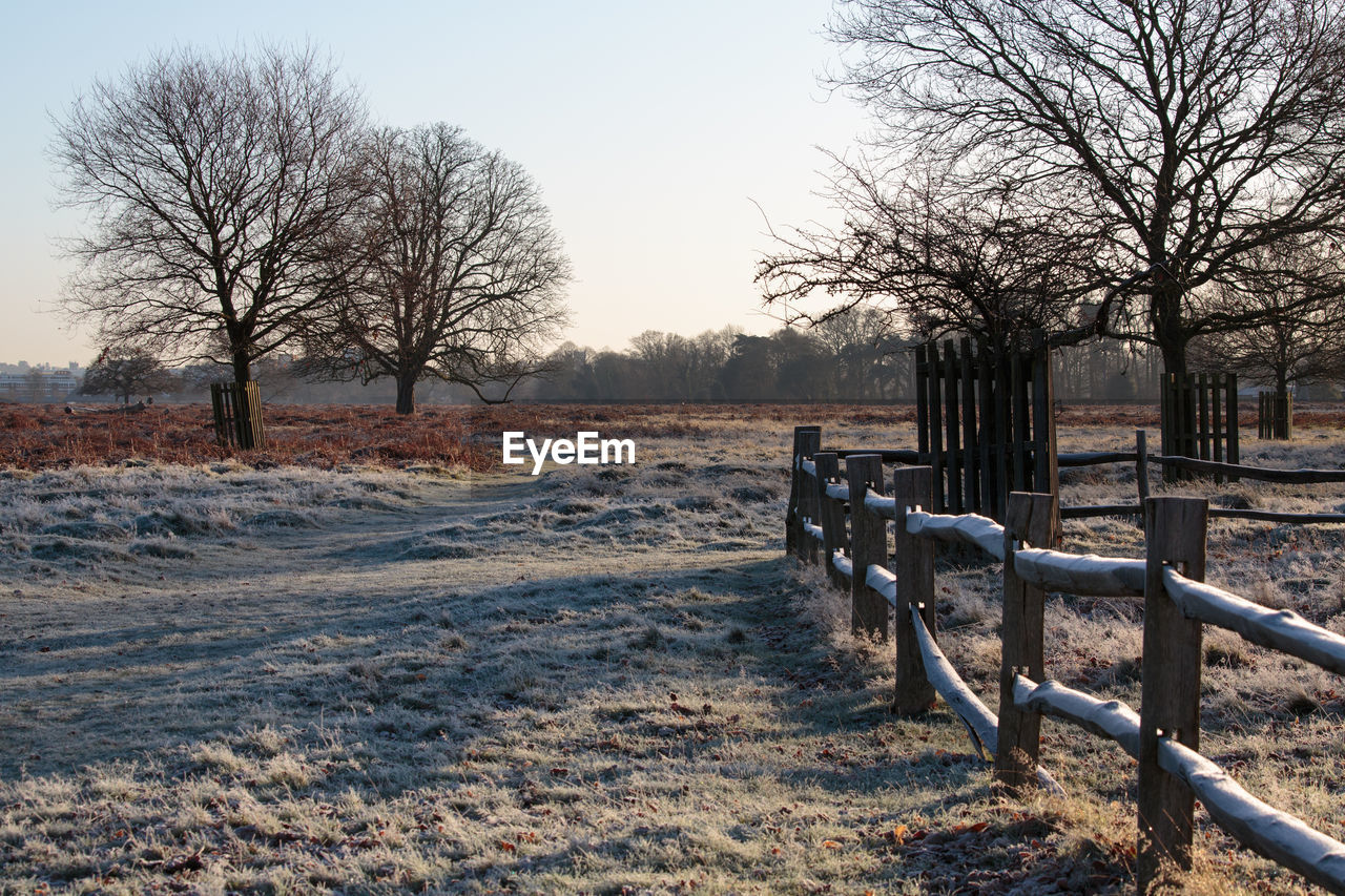 Empty park bench on field against clear sky