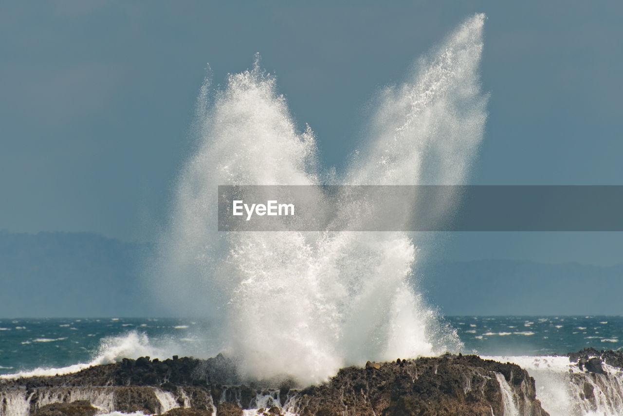 Waves splashing on sea against sky