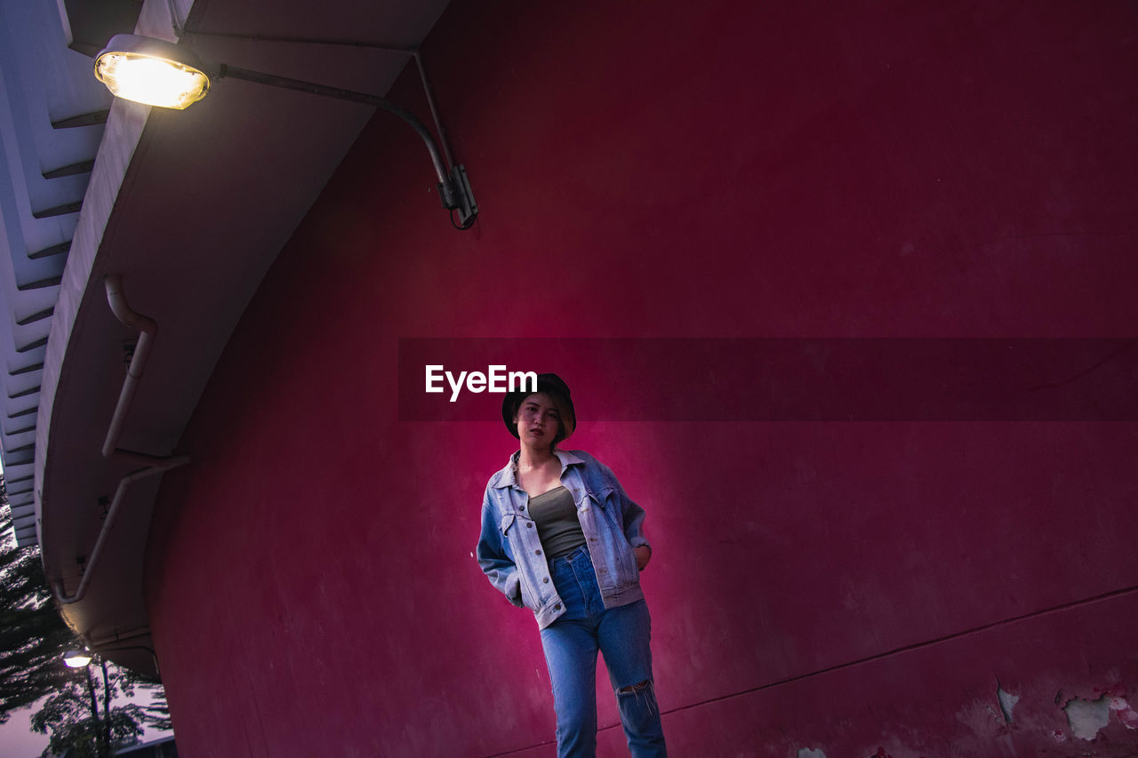 Portrait of young woman standing against wall