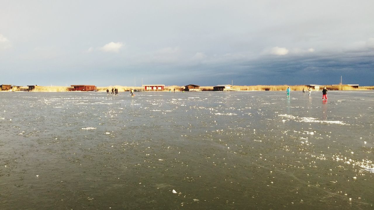 PEOPLE ON BEACH BY SEA AGAINST SKY