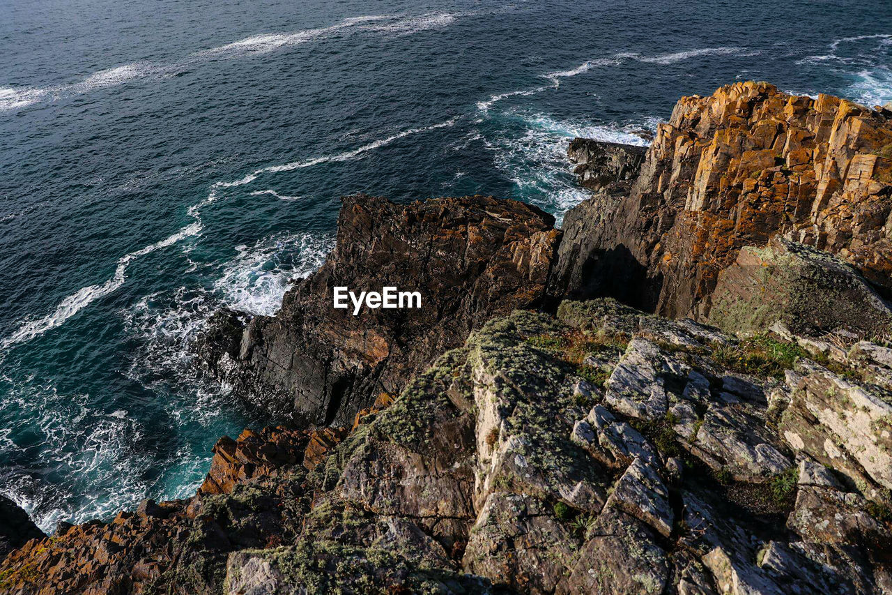 High angle view of rocky mountains at sea shore