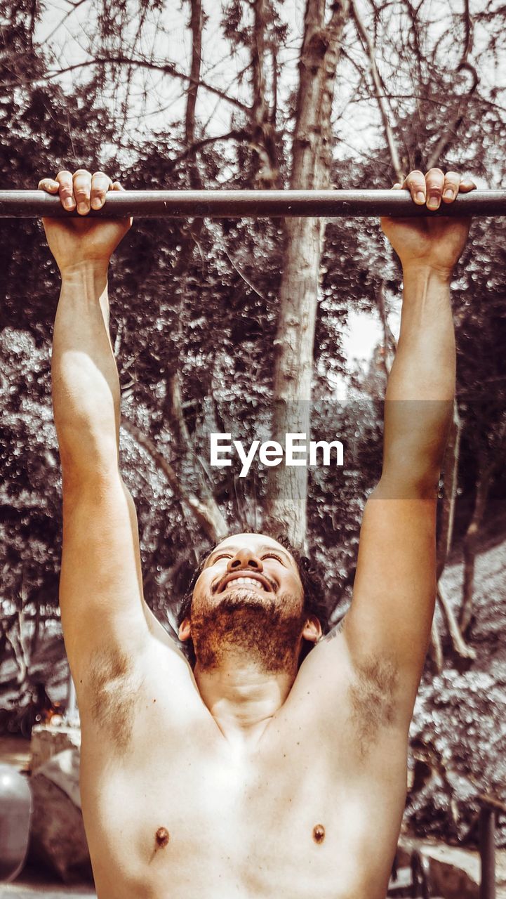 Man hanging from metal rod against trees