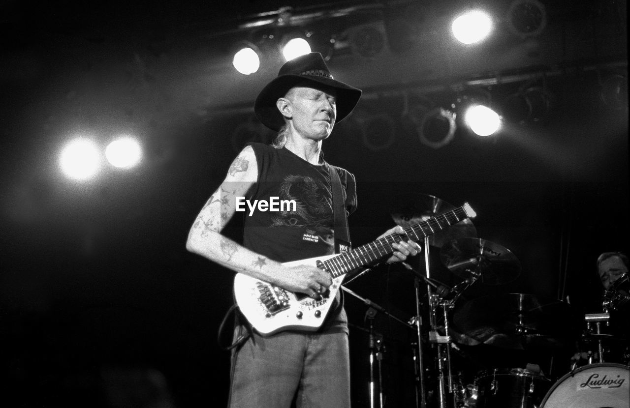 FULL LENGTH OF MAN WITH GUITAR IN ILLUMINATED LIGHT