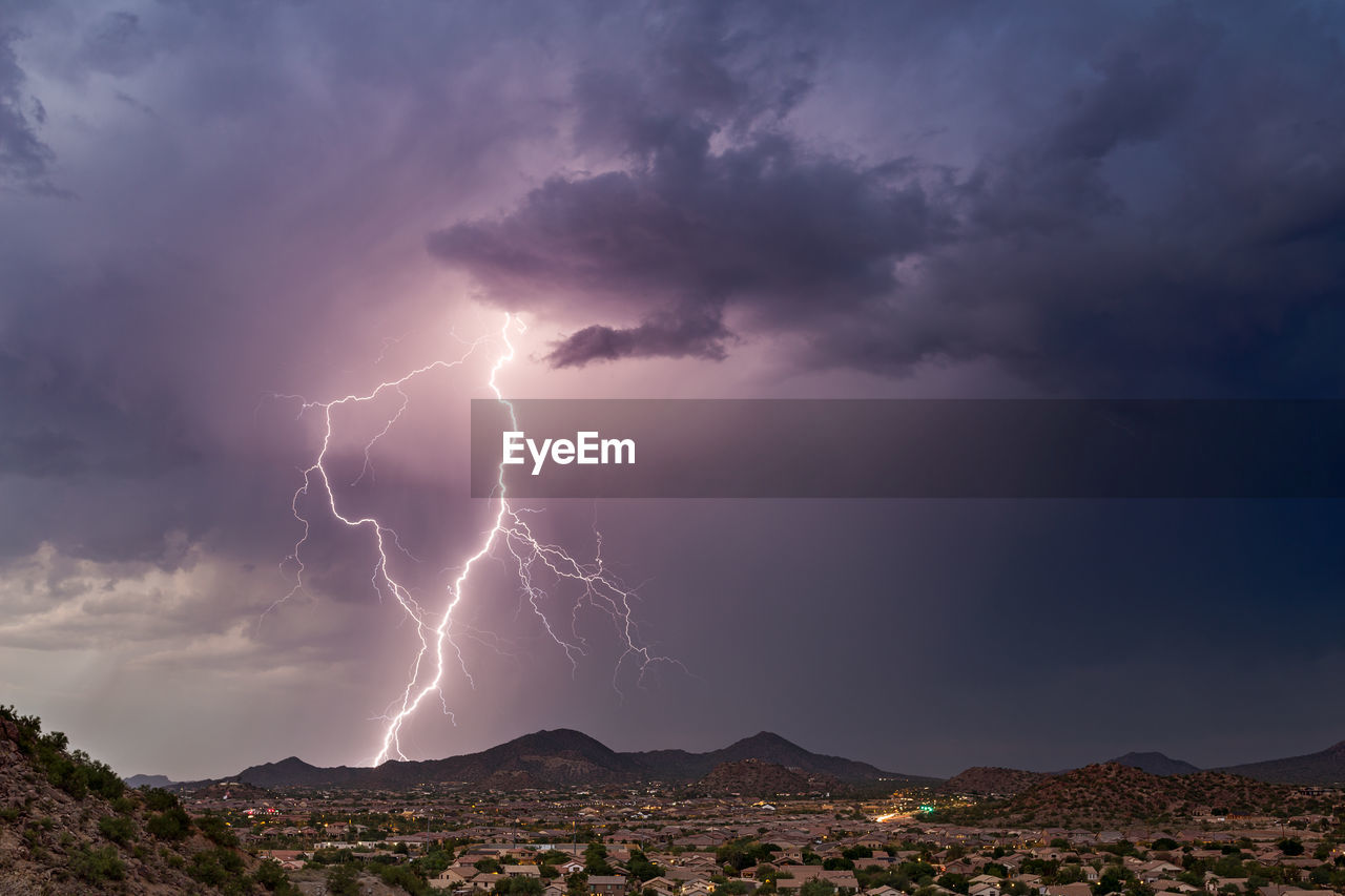 Low angle view of lightning over mountains against dramatic sky