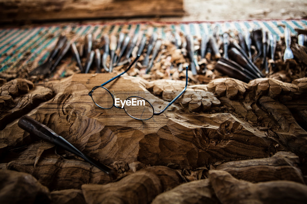 Close-up of eyeglasses and work tool on wood