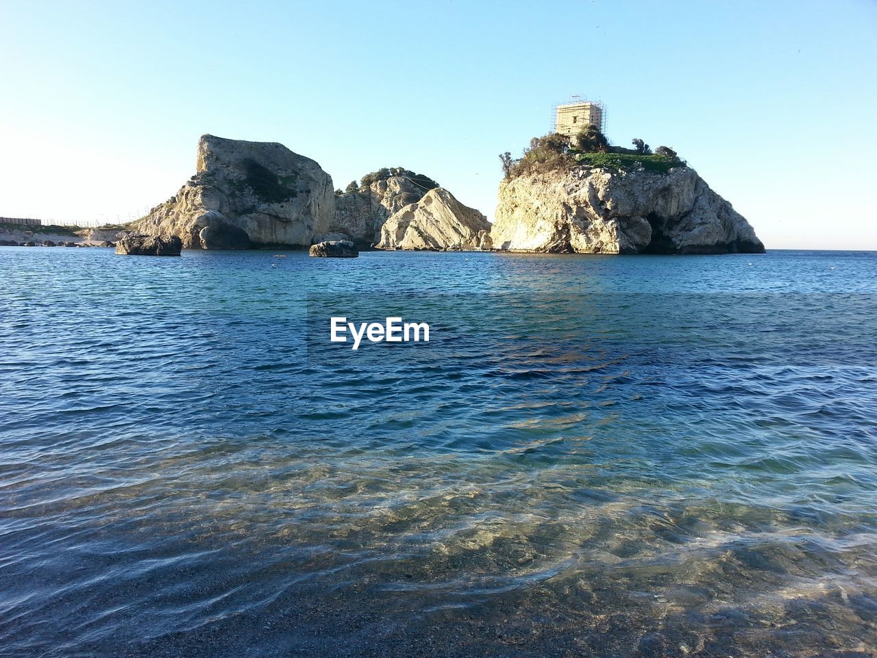 Scenic view of sea against rocks and clear sky