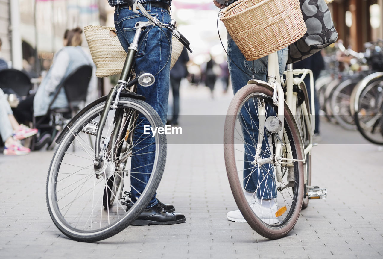 Low section of senior couple standing with bicycles on street