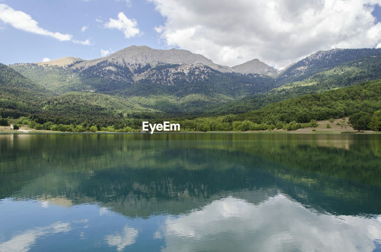 Reflection of mountains in lake against cloudy sky
