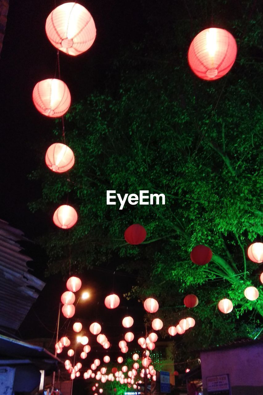 LOW ANGLE VIEW OF ILLUMINATED LANTERNS HANGING BY TREES