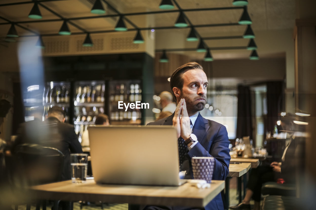 Worried businessman looking away while sitting in restaurant