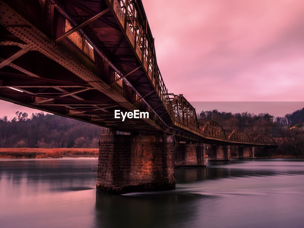 Low angle view of bridge over river at sunset