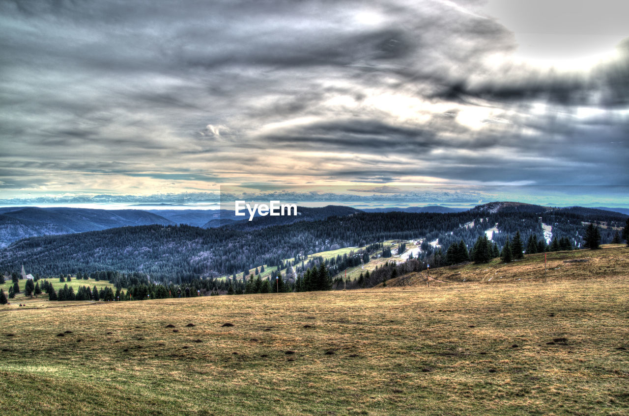 Scenic view of landscape and mountains against cloudy sky