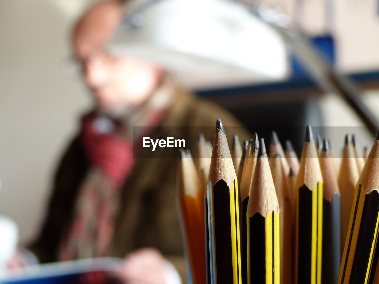 Close-up of pencils in container at table by man at home